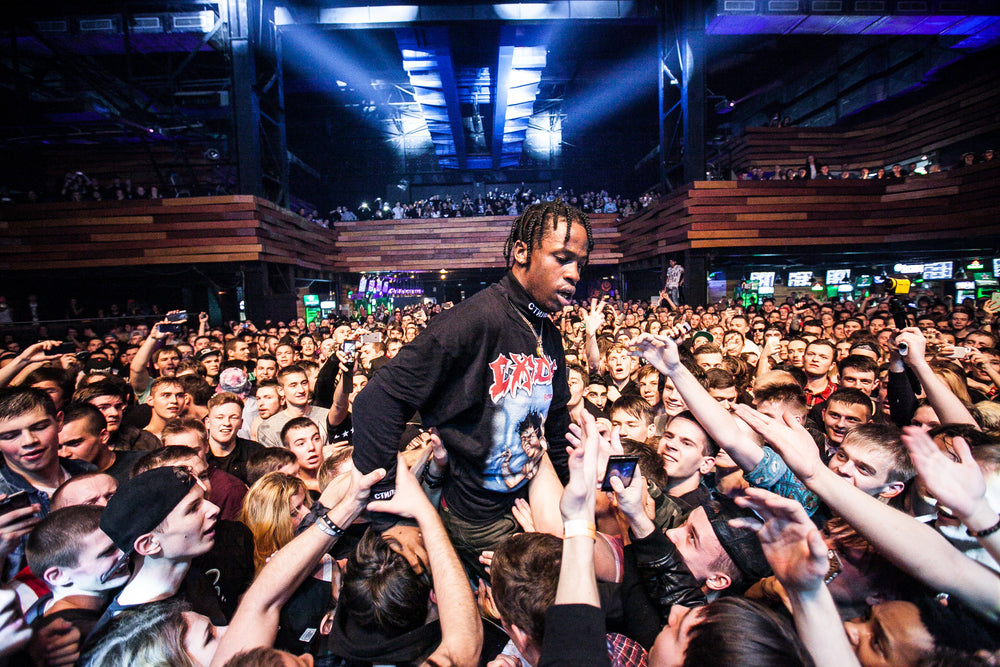 Travis Scott performing live music show concert on night club stage.